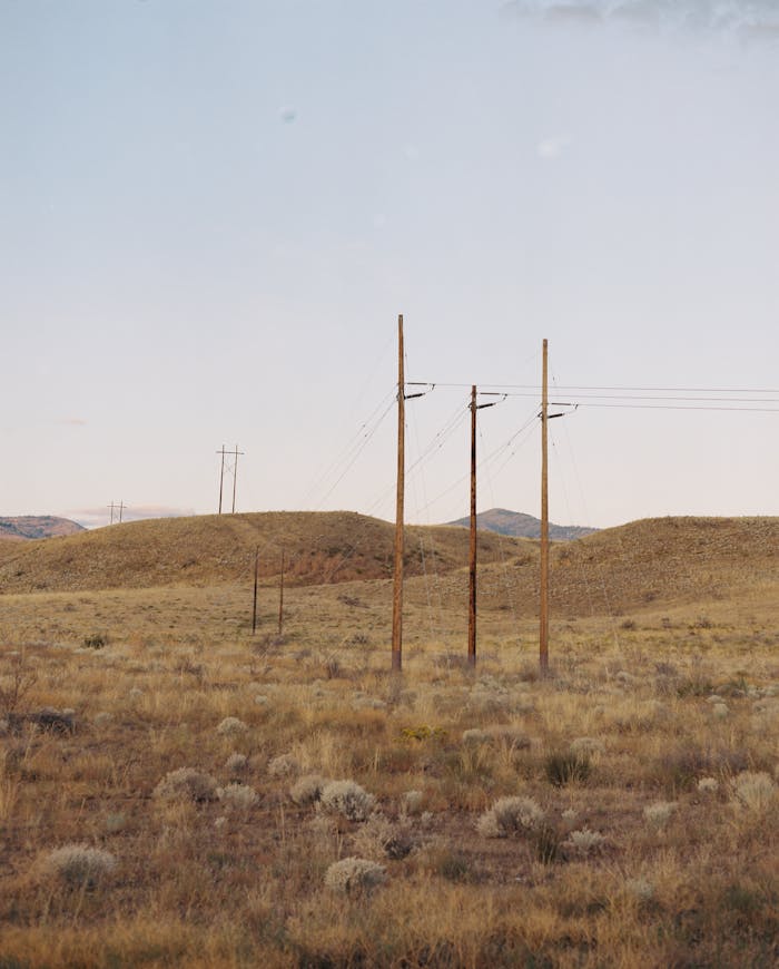 why-choose-us Beautiful rural landscape with power lines crossing grassy hills under a clear sky.